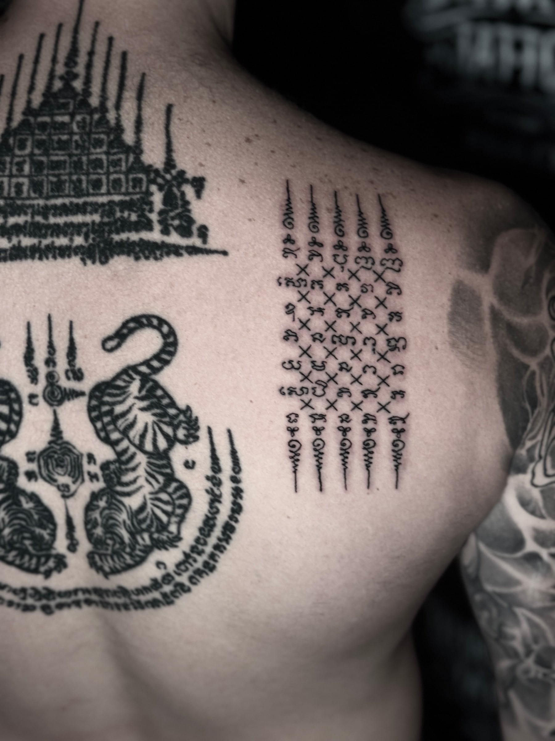 Close-up Hah Taew (Five Lines) Sak Yant on the right shoulder blade with Gao Yord and Suea Koo designs on the upper back at Bloodline Tattoo Phuket.