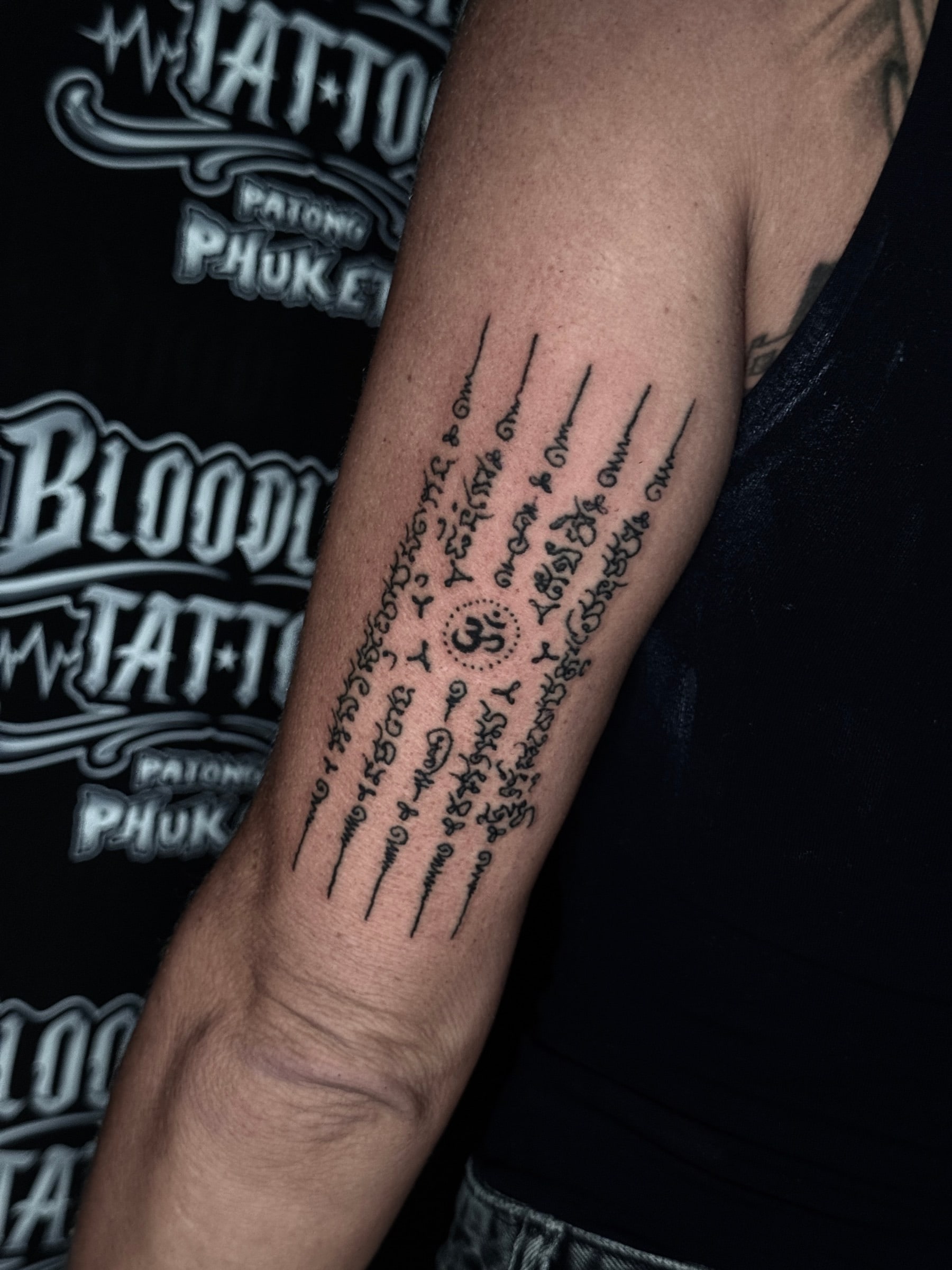 Hah Taew (Five Rows) Sak Yant with five Khom script columns and a central Om symbol on the inner forearm at Bloodline Tattoo Phuket.