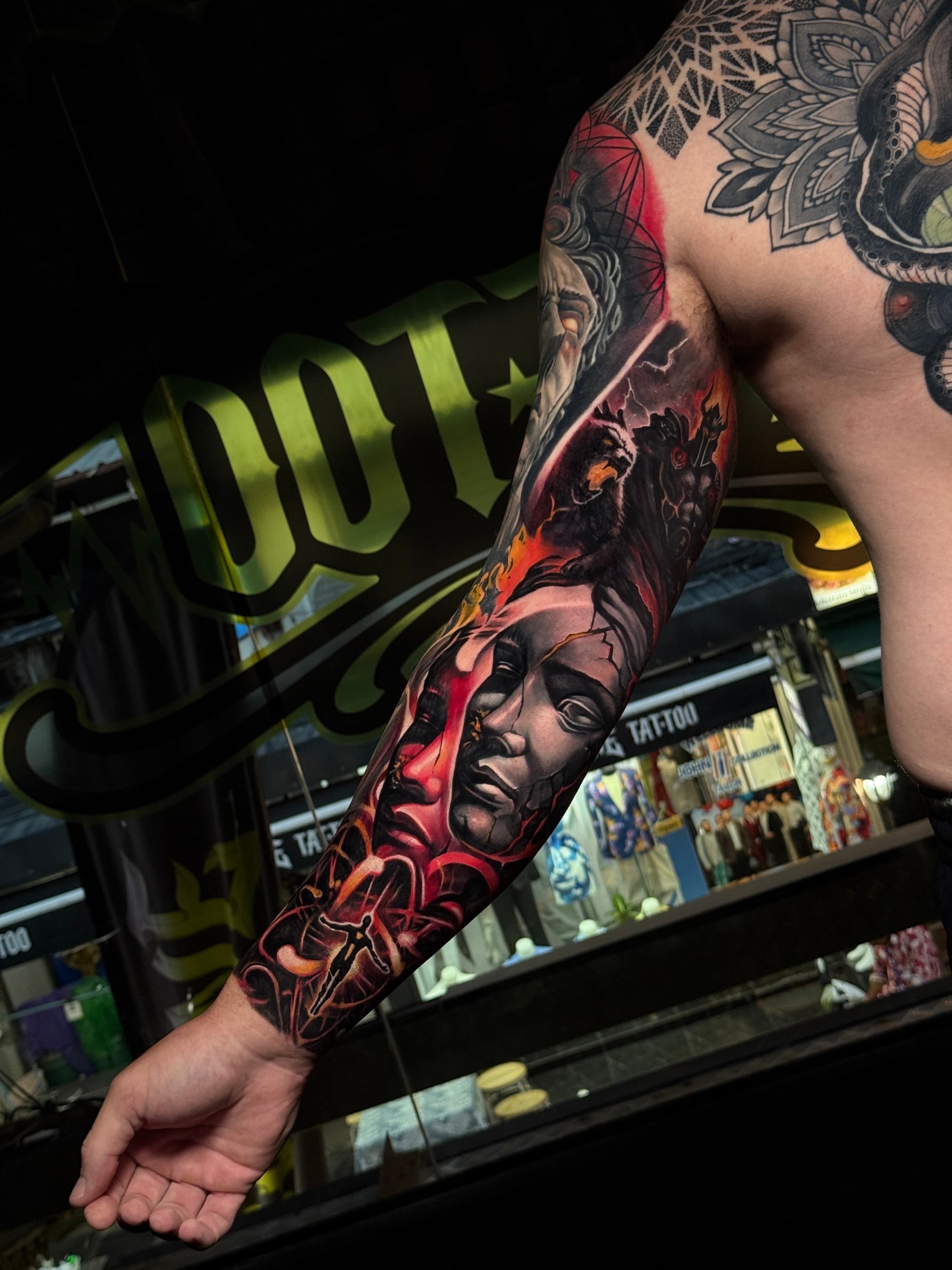 Dark fantasy colour sleeve with a cracked stone face, a snarling demon in red flames, and a geometric mandala on the shoulder at Bloodline Tattoo Phuket.