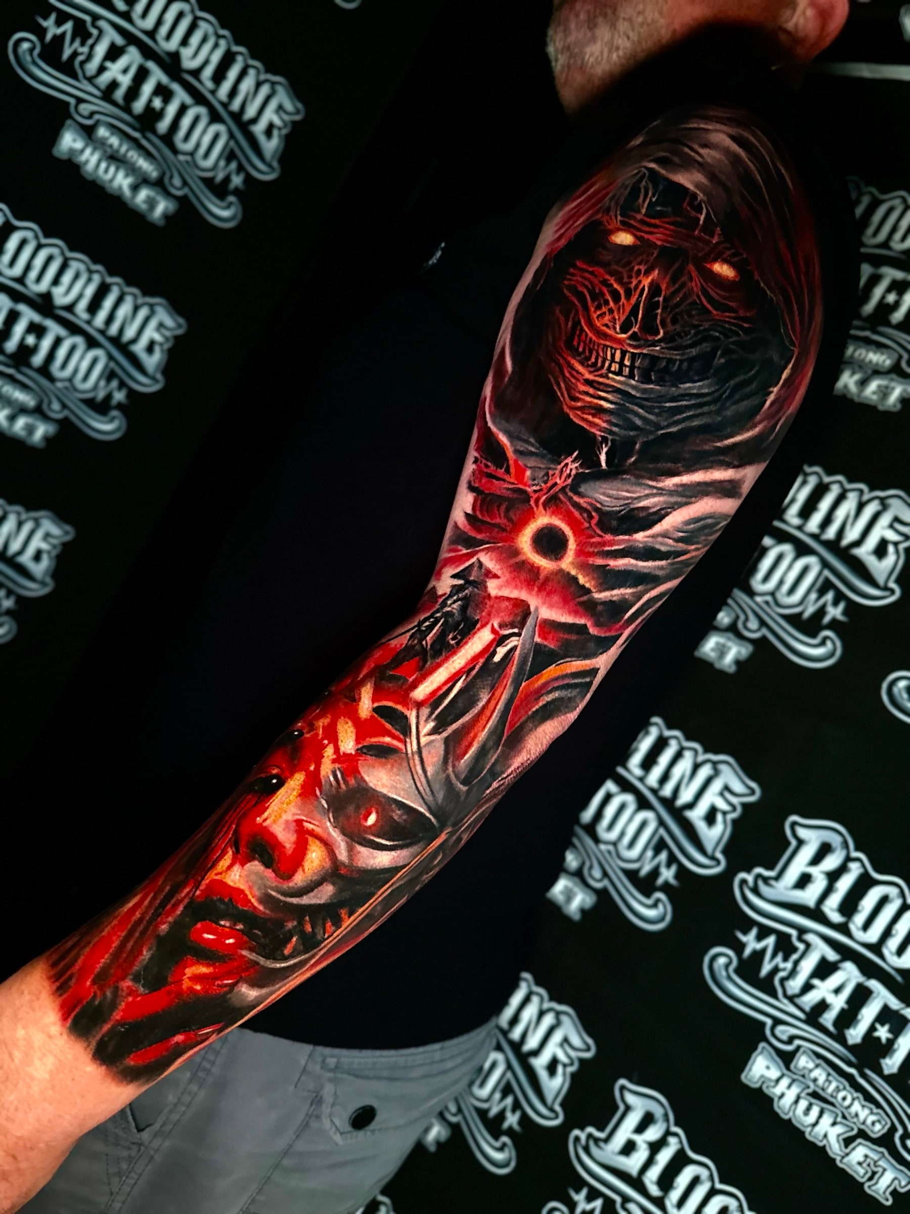 Dark fantasy colour sleeve with a hooded wraith, a glowing eclipse portal, and a layered Oni demon mask in red and orange at Bloodline Tattoo Phuket.