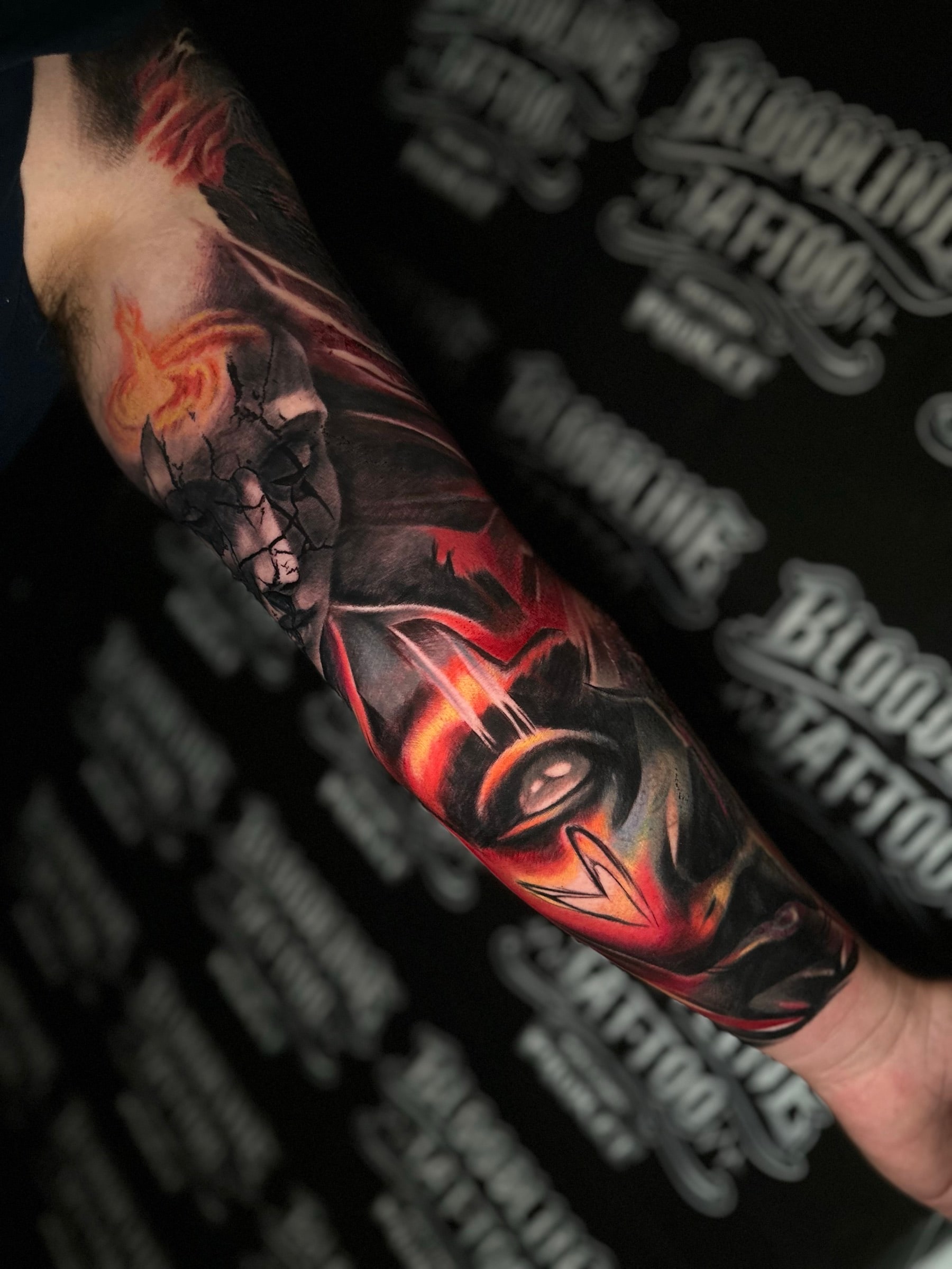 Colour forearm tattoo of a cracked porcelain woman face with flame motifs and a glowing fiery eye symbol below at Bloodline Tattoo Phuket.