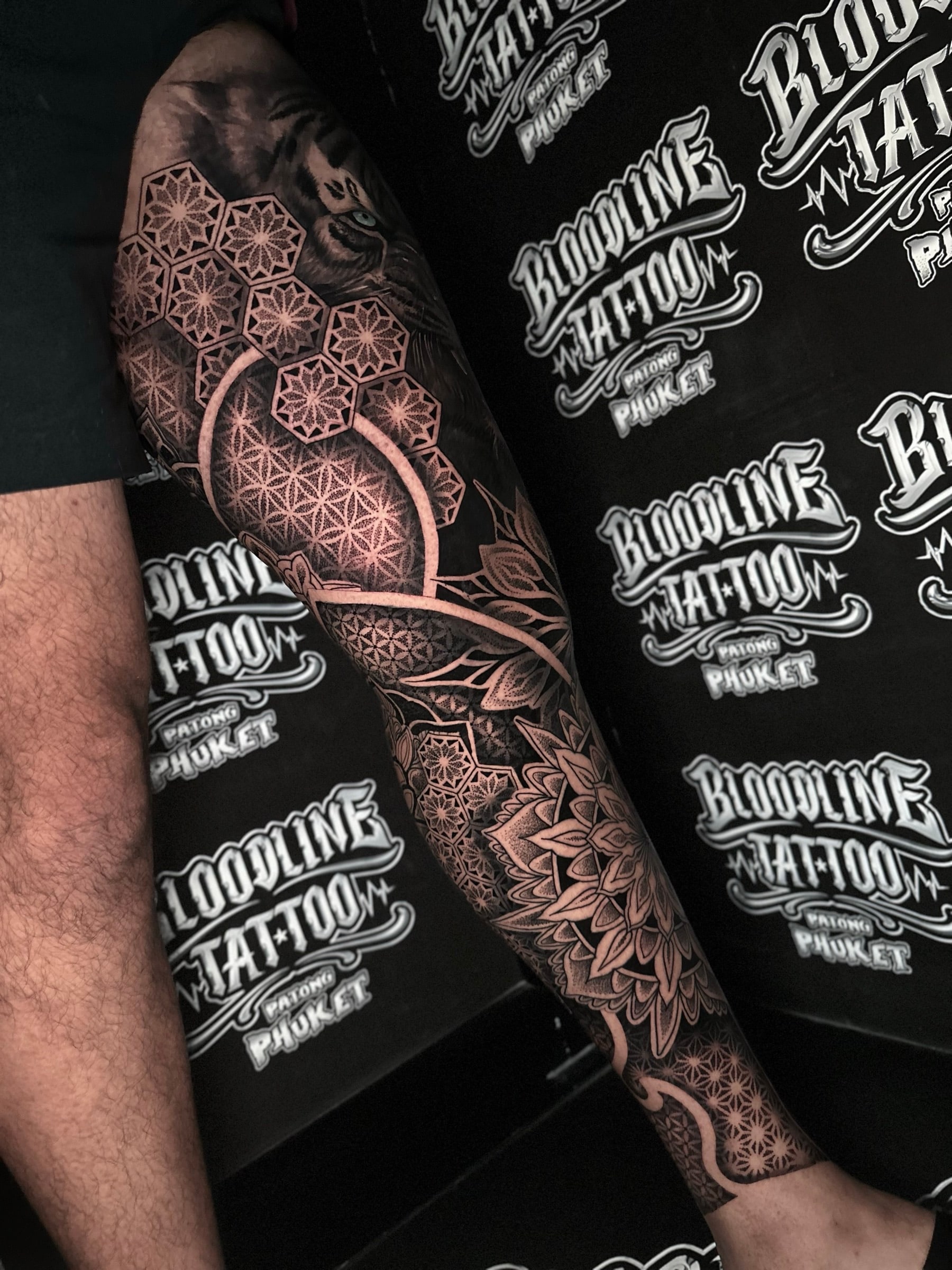 Full leg mandala sleeve with a peeking tiger, honeycomb hexagon grids, Flower of Life panels, and a calf lotus mandala at Bloodline Tattoo Phuket.
